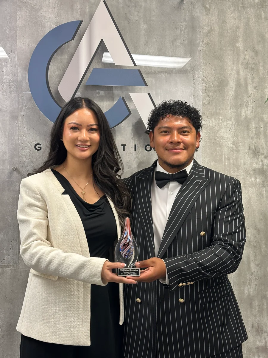 Two GA Jersey Village team members with an award at the office