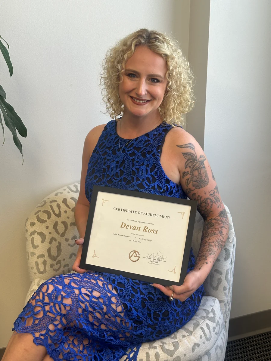 A GA Jersey Village team member with a certificate of achievement