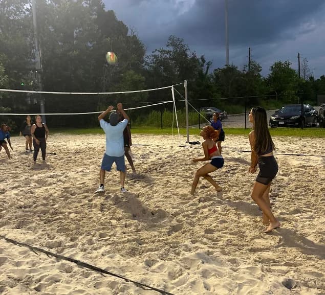 GA Jersey Village team members playing beach volleyball at a team outing