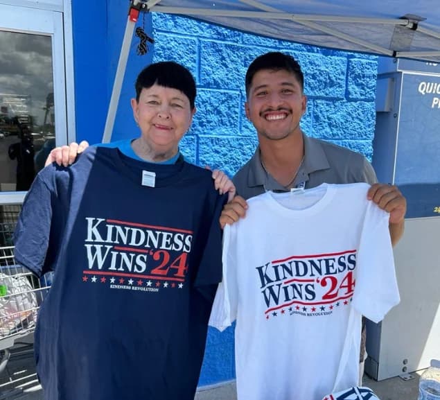 Team members holding Kindness Wins campaign shirts
